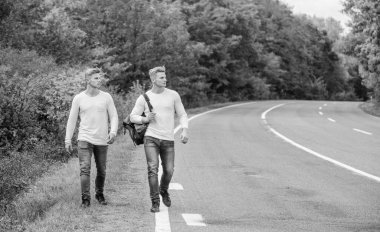 Boş yolda otostop çekerek. Otostop yaparak. Yolculuk. Yolculuk tutkusu konsepti. Arkadaşlarla yürüyüş yapmak iyidir. Kendilerini bulmaya gittiler. Seyahat ve otostop. Yol boyunca yürüyen ikizler