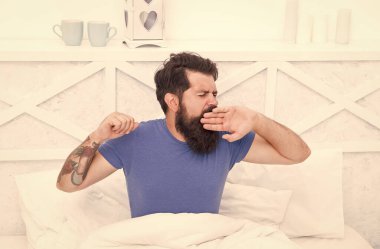 Hoş bir uyku saati. Vahşi erkek odada vakit geçiriyor. Rahat yaşam tarzı konsepti. Sakallı adam yatakta esniyor. Sabah uyanırsın. Bekar rahat hisset. Yatak odasında esneyen adam. Tembel Pazar