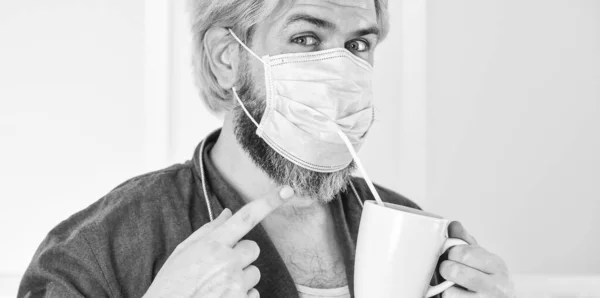 Alvorlig om hygiene. En fyr med maske drikker kaffe med sugerør. Dekk munn og nese med maske og sørg for at det ikke er hull mellom ansikt og maske. Helt beskyttet. Beskyttelse mot coronavirus med maske – stockfoto