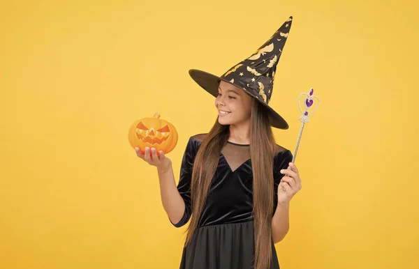 Childhood autumn holiday. teen girl ready to celebrate. costume party fun. happy halloween. child in witch hat. kid hold magic wand and pumpkin. witchcraft and enchantment. Welcome to the Nightmare — Stock Photo, Image