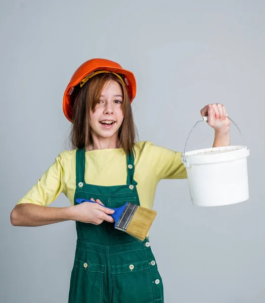 Tini lány munkás -ban védő sisak és egyenruha használat festmény ecset és vödör, munkanap — Stock Fotó