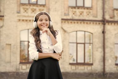 Dışarıda mutlu bir çocuk. Neşeli bir kız öğrenci. Müzik dinleyen kız öğrenci. Mutlu çocukluk kavramı. Uluslararası Çocuk Günü. Benimle şarkı söyle. Gülümseyen öğrenci. Gerçek başarı. Mutlu şarkı. Boş zaman ve dinlenme