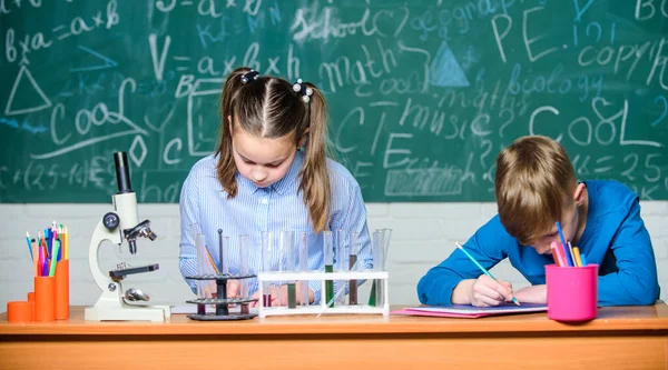 Lekce chemie. Školní laboratoř. Dívka a chlapec chytří studenti provádějí školní experiment. Popište poznámkový blok o chemické reakci. Školní vzdělání. Chemická analýza. Děti pilně studují chemii — Stock fotografie