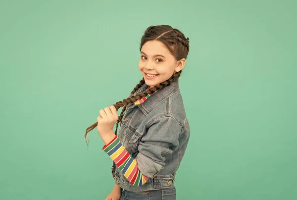 Cabelo longo pode ser divertido e brincalhão. Menina feliz em tranças fundo azul. A criança segura a trança longa. Penteados da moda. Estimulantes do crescimento do cabelo longo. Extensões de cabelo. Cabeleireiro de salão — Fotografia de Stock