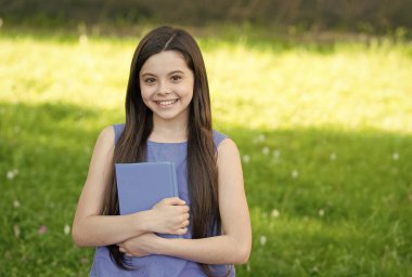 Açık havada kitabı olan küçük zeki kız güneşli bir gün, kendini eğitme konsepti.