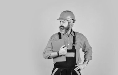 Tadilat için malzeme al. Sakallı bir dükkancı. Kontrol listesi. Teftiş. Kontrol konsepti. Belgelerle ustabaşı. İnşaat malzemeleri teslimatı. Elinde dosya tutan kasklı bir adam bilgi arıyor.