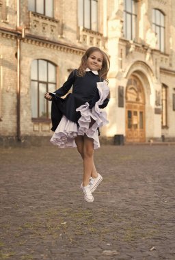 Hareketlerinle kendini ifade et. Dansçı kız dışarıda üniforma giyiyor. Havada enerjik bir çocuk. Dans eğitimi. Dans okulu. Okul modasına geri dönelim. Enerjini arttır.