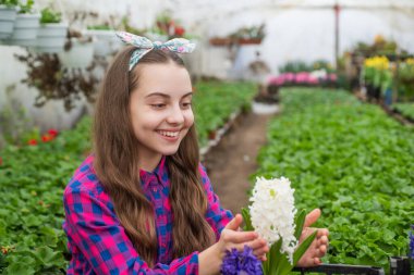 Şuna bir bak. Çocuklar için bahçe işleri. Seradaki mutlu genç kız çiçekçi. bahar ve yaz