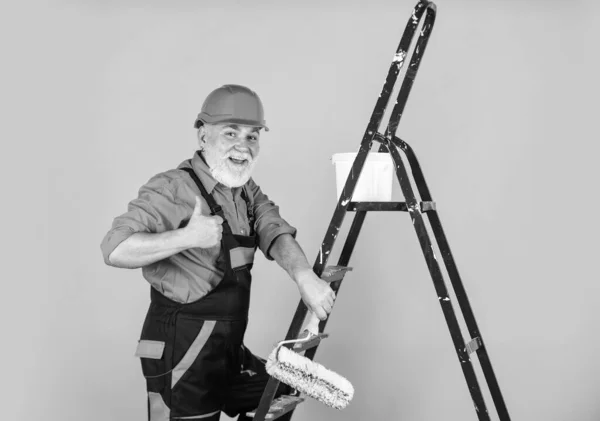 Homem na parede de pintura de roupas de trabalho em quarto vazio. pintor em geral e tampa com balde de tinta. construtor trabalhador pintura fachada. isolamento térmico funciona. Escadaria do pintor. Para fazer reparos — Fotografia de Stock