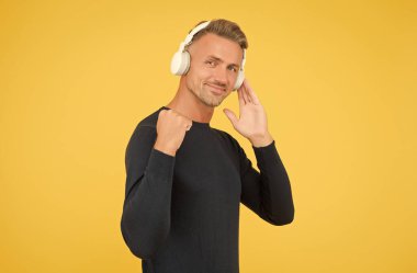 Seslendirmeyi gerçekten seviyorum. Kaliteli kablosuz cihaz. Kulaklık takan neşeli bir adam. Müzik ve dijital teknoloji. Kitap ve elearning. Kulaklık takıp şarkı dinleyen olgun, tıraşsız bir adam. müzik uygulaması çalma listesi