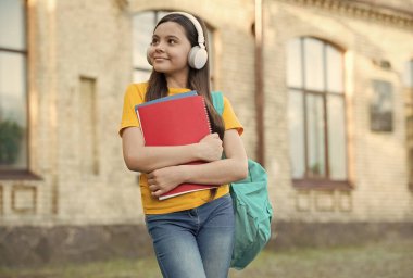 En sevdiği melodi. Okula dönüyorum. Genç kız, sesli kitabı dinle. Okul bahçesinde defteri olan bir çocuk. Mutlu çocuk klasörü tutuyor. Küçük kız dışarıda kulaklık takıyor. Modern hayatta okul eğitimi