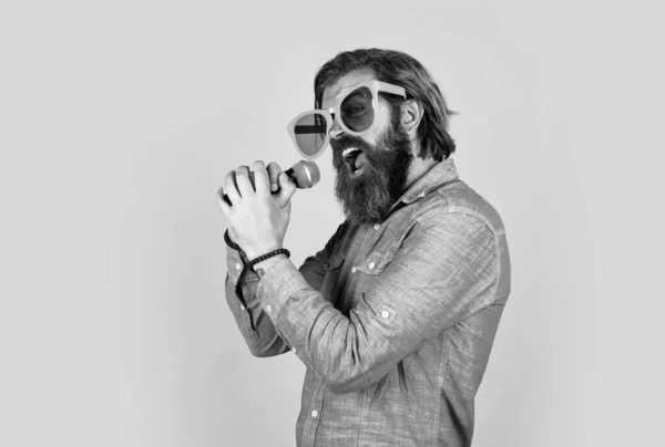 Prendi una nota alta. brutale hipster maschile con microfono. scuola vocale. stile musicale preferito. concetto di musica. esecutore divertirsi. maturo barbuto uomo in divertente partito occhiali cantare canzone — Foto Stock