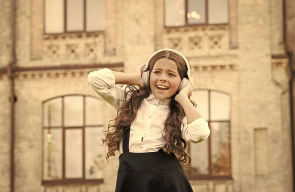Schönes Lied. Kind in digitalen Kopfhörern. kleines studentisches Mädchen hört Musik im Freien. zurück zur Schule. kleines Mädchen, das klug und intelligent aussieht. glückliches Schulmädchen in stilvoller Uniform. Kinderglück — Stockfoto