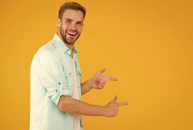 Erkek yüz bakımı ve güzellik. Ürün sunumu. Tıraşsız, parmakla işaret eden mutlu adam. Reklam için kopyalama alanı. Sıradan gömlek giyen sakallı seksi adam. Erkek bahar modası