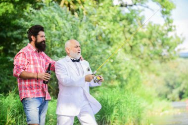 Sakallı adam ve zarif iş adamı birlikte balık tutuyor. Balık tutma becerileri. Oltayı oltaya getirin. Balık tutmak ve bira içmek. Erkekler doğayı rahatlatıyor. Eğlen ve rahatla. Hafta sonu zamanı