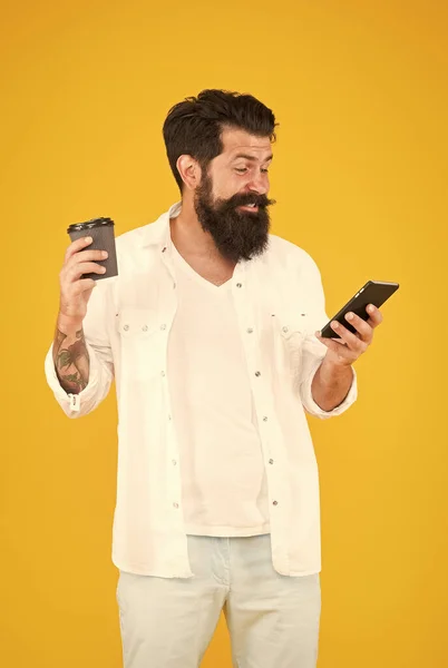 Felice uomo barbuto maturo piace leggere buone notizie al telefono mentre beve caffè del mattino, gioia e piacere — Foto Stock