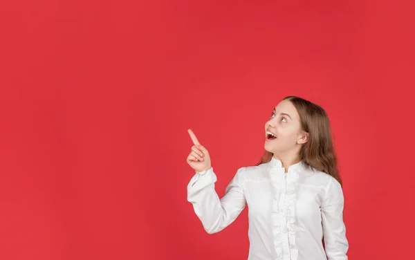Niño sorprendido en camisa blanca señalando el dedo en el espacio de copia de fondo rojo, anuncio — Foto de Stock