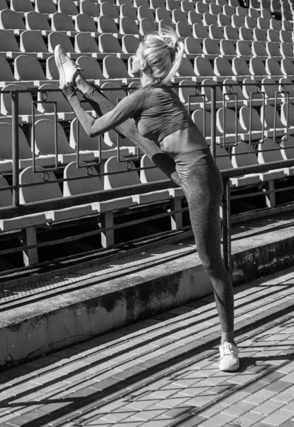 Σέξι γυναίκα που τεντώνεται έξω. Αθλητική γυναίκα στην εκπαίδευση αθλητικών ειδών στο στάδιο. Ζέστανε τους μυς της. γυναικείο εύκαμπτο σώμα. γιόγκα και πιλάτες. σπορ υγιεινό τρόπο ζωής. προπονητής φυσικής κατάστασης — Φωτογραφία Αρχείου