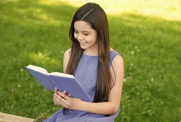 Pequena menina feliz lendo livro ao ar livre dia ensolarado, conceito história legal — Fotografia de Stock