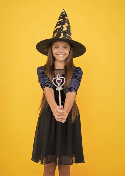 Strega di Halloween. infanzia felice. Una ragazzina col cappello da strega. il bambino allegro crea miracoli con bacchetta magica. festa in costume di carnevale. Dolcetto o scherzetto. celebrare le vacanze — Foto Stock