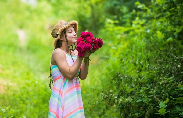 Niña feliz en sombrero de paja con flores de rosas en la naturaleza de verano, primavera — Foto de Stock