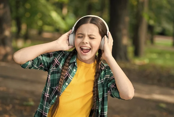 Tudo menos música. Menina feliz cantar música verão ao ar livre. Uma criança usa auscultadores a tocar música. Vida moderna. Nova tecnologia. Férias de verão. Lazer e prazer. Entregue-se ao sulco — Fotografia de Stock