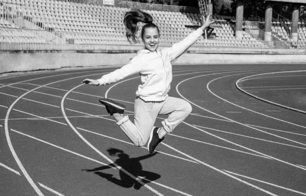 Energisk flicka barn hoppa på friidrott spår fysisk utbildning utomhus, sport — Stockfoto