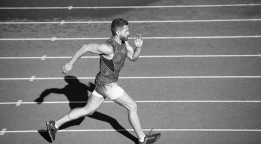 Spor giyinen erkek sporcu hızlı koşar koşu pistinde, mesafe