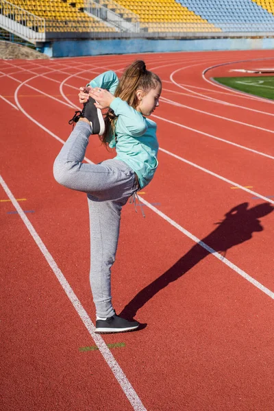 Τεντώνομαι για καλύτερη ευελιξία. Ευέλικτο παιδί κρατά το πόδι στέκεται στο πόδι. Άσκηση ευελιξίας. Απλή ρουτίνα — Φωτογραφία Αρχείου
