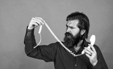 Olgun erkek, kırık retro telefonu tutar. Sakallı ve bıyıklı adam çağrıya cevap veriyor. Telefon görüşmesi. Sakallı adam. Modern hayatta iletişim. Telefonda arkadaşınla konuş.