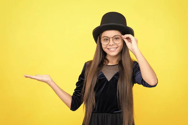 Ευτυχισμένο παιδί με γυαλιά μόδας με εμφάνιση κόμμα κρατήστε το άδειο χέρι για αντίγραφο χώρο κίτρινο φόντο, προϊόν — Φωτογραφία Αρχείου