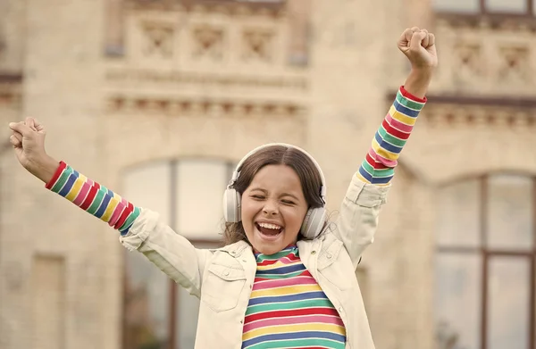 El niño canta en el patio de la escuela. positivo y colorido. El niño tiene un descanso musical. chica con auriculares. niña bonita usar auriculares inalámbricos. de vuelta a la escuela. educación moderna con nuevas tecnologías — Foto de Stock