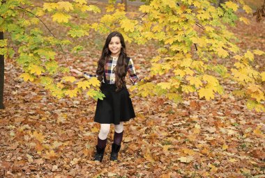 Uzun saçlı sevimli çocuk sonbahar doğasının ve havanın tadını çıkar.