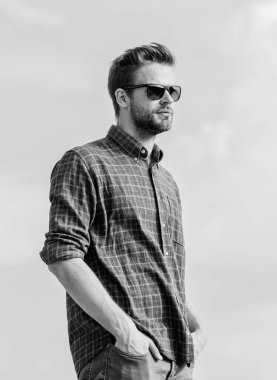 Ultraviyole koruma kavramı. Mükemmel görüş. Göz sağlığı. Modaya uygun güneş gözlükleri. Erkek gözlüklü model açık havada mavi gökyüzü arka planı. Yakışıklı adam güneş gözlüğü takıyor. Moda gözlüklü hippi.