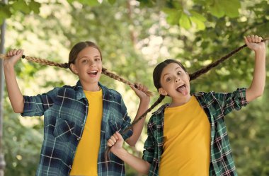 Komik çocuklar uzun saç örgü örerler. Ağızlarını buruştururlar. Yazın açık havada, kuaförde.