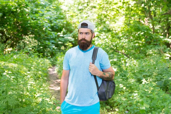 Hombre barbudo maduro con barba y bigote en camisa de verano y mochila de sujeción de gorra en el bosque, viaje deportivo — Foto de Stock