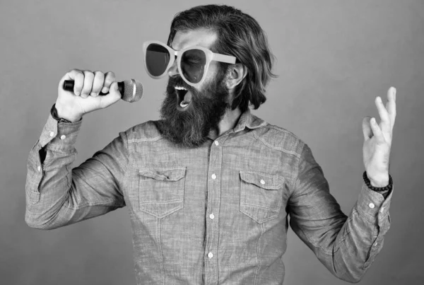 Uttrycka känslor. Glad skäggig man bär roliga festglasögon. mogna event manager hålla mikrofon. Ha lite kul. Födelsedagssångerska. fira högtiden. Hipster sjunger en sång. musik — Stockfoto