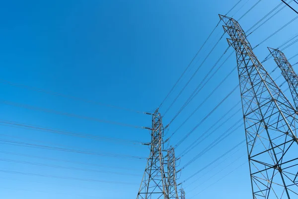 Linee elettriche che producono energia con su torre elettrica su sfondo cielo blu, tensione. — Foto Stock