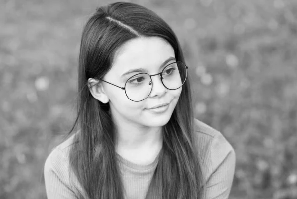 Niña usar gafas de borde vintage verde césped fondo, concepto de salud de los ojos —  Fotos de Stock