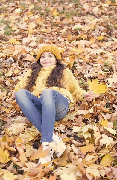 Like a fallen leaf on autumn day. Excited child lying in autumn leaves. Little girl in casual fashion wear outdoor. Autumn look of small fashion model. Cold weather fashion for kids — Stock Photo, Image