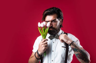 Tarz sahibi vahşi sakallı erkek lale buketi tutuyor, anneler günü.