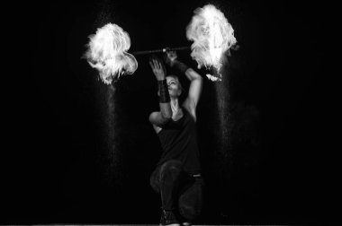 Yüksek enerjili ateş dansçısı. Şehvetli ateş dansçısı karanlıkta alevli bir değnek çeviriyor. Ateş performansı.
