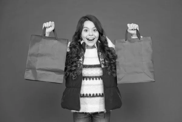 Muchacha del niño extremadamente feliz con pelo largo usar ropa de abrigo y llevar a cabo paquetes presentes después de comprar, compra de año nuevo —  Fotos de Stock