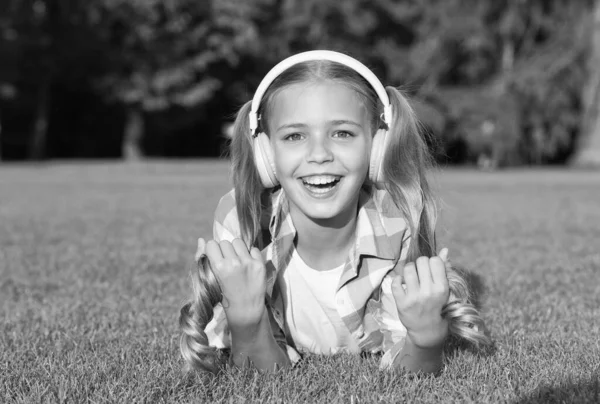 긴 머리의 꼬리를 가진 행복 한 소녀는 현대의 헤드폰 자연환경, 영어에서 외국어 수업을 듣기를 즐긴다 — 스톡 사진