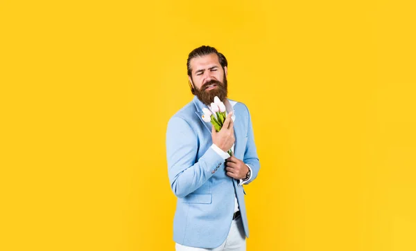 春のプレゼント。花束を持った真の紳士。恋愛デートのコンセプト。チューリップの花で正式に髭を生やした男。エレガントなビジネスマンは正式なイベントのためのエレガントなアパレルを身に着けている — ストック写真