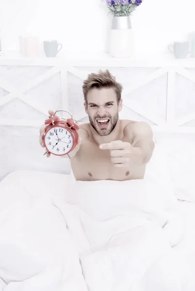 Look at this clock. Stressful man point finger at clock face. Sexy guy slept through alarm clock. Lack of time. Being late. Morning routine. Nightmare. Ghastly dreams. Waking up. Awakening