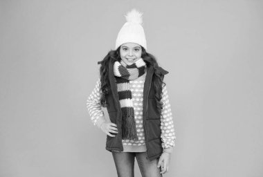 Uzun kıvırcık saçlı mutlu genç kız Noel tatillerinde, kış giysilerinde, kabarık yelek ve örgü giyer.