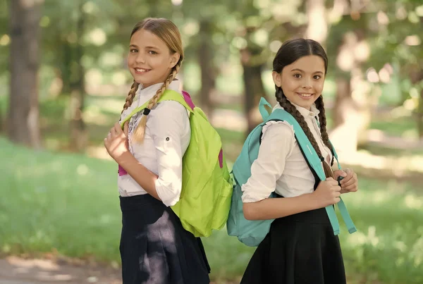 Crianças felizes carregam sacos escolares em uniforme formal ao ar livre, de volta à escola — Fotografia de Stock