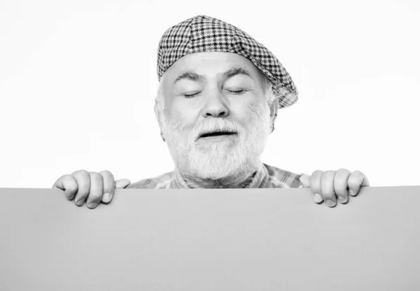 Senior man met een baard gluurt uit banner plaats informatie. Gepensioneerde houdt poster informatie kopieerruimte. Timing en schema. Publieke informatie. Reclame voor ouderen. Aankondigingsconcept — Stockfoto