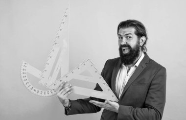 Yüzü gülen aritmetik öğretmeni açıölçer ve üçgen tutuyor, kök öğreniyor..